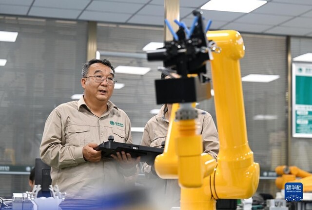 张黎明和同事在调试第四代配网带电作业机器人（2022年9月8日摄）。新华社记者 赵子硕 摄